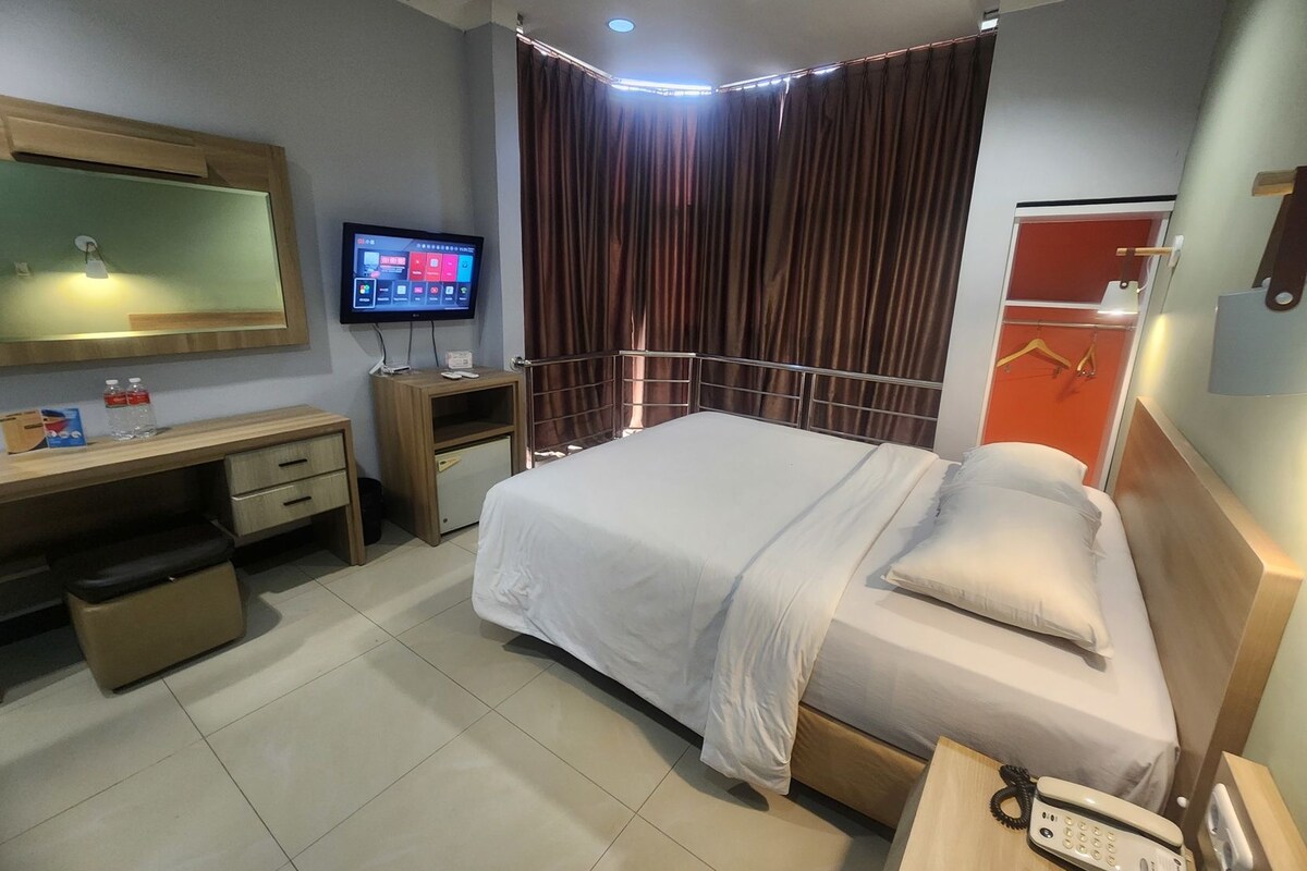 Ein Hotelzimmer mit Bett, Schreibtisch, Fernseher und Telefon.