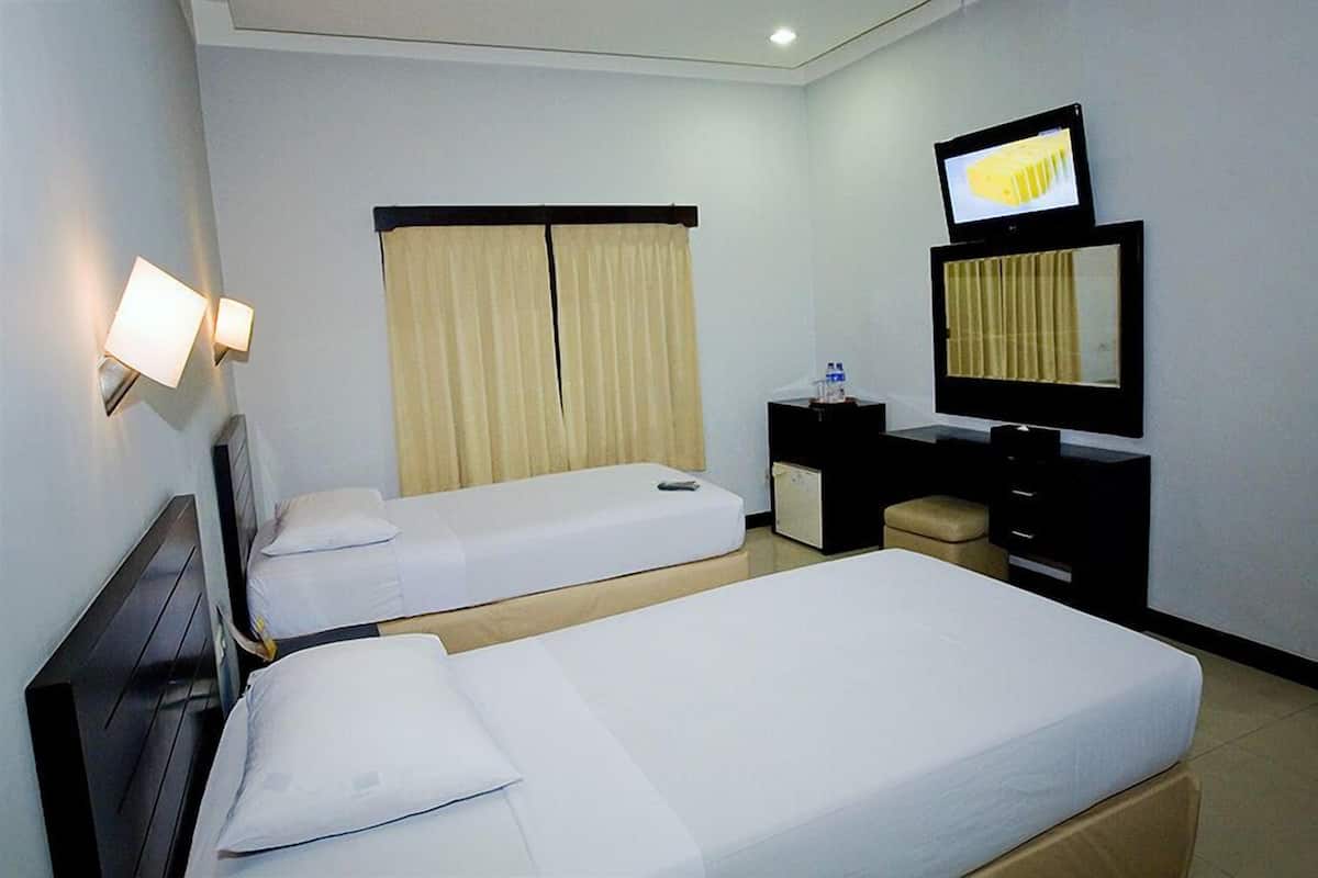 A hotel room with two single beds, a desk with a chair, a television, and a minibar.