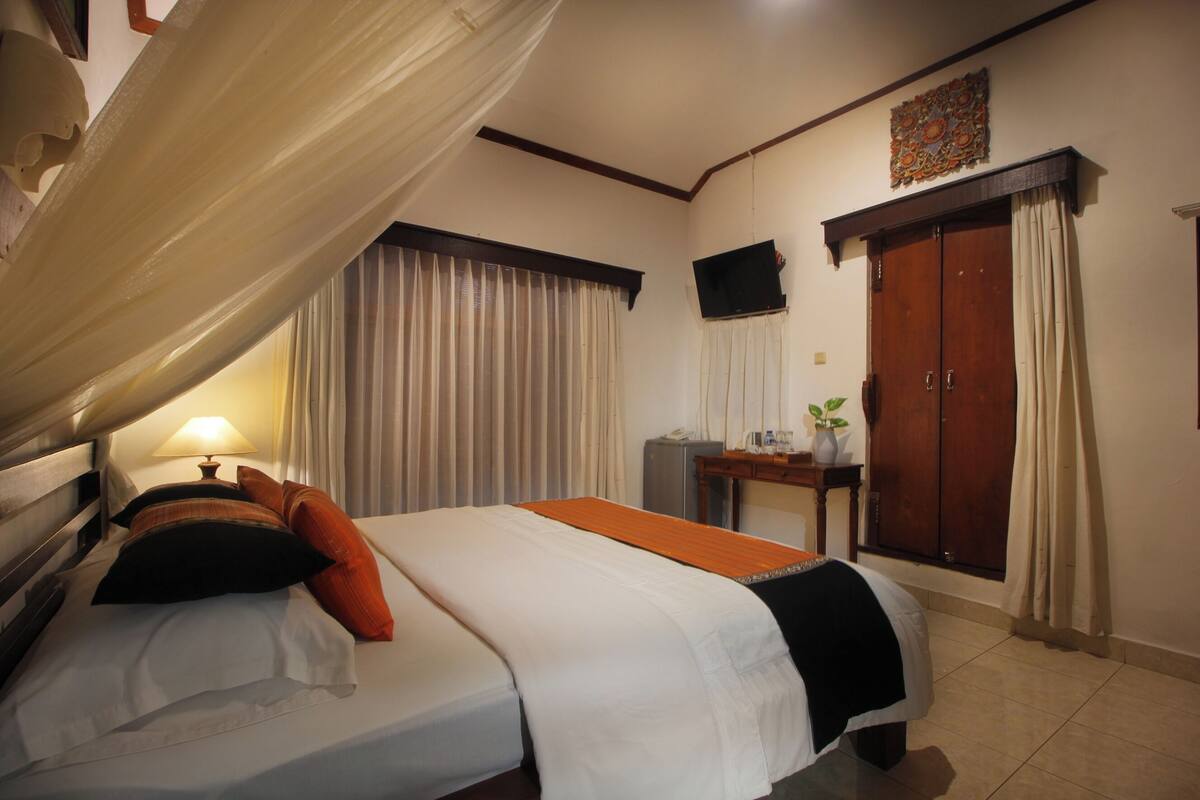 A hotel room with two beds, a desk, a TV, and a wardrobe.
