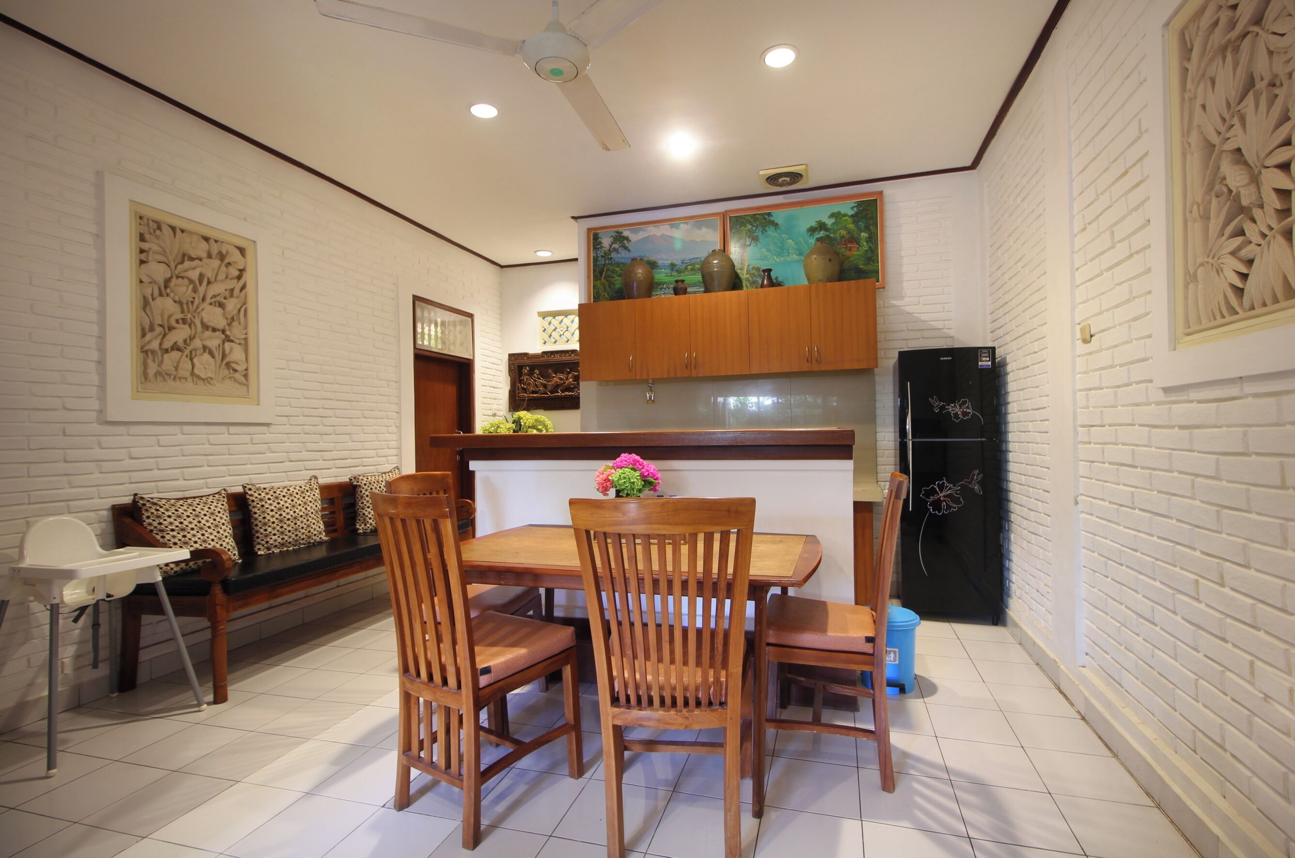 A dining area with a wooden table, chairs, a bench, and a ceiling fan.