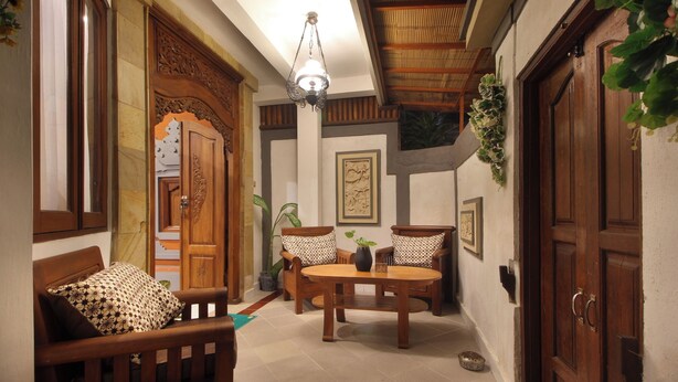 Una habitación acogedora con un sofá de madera, una mesa redonda y un mueble de madera.