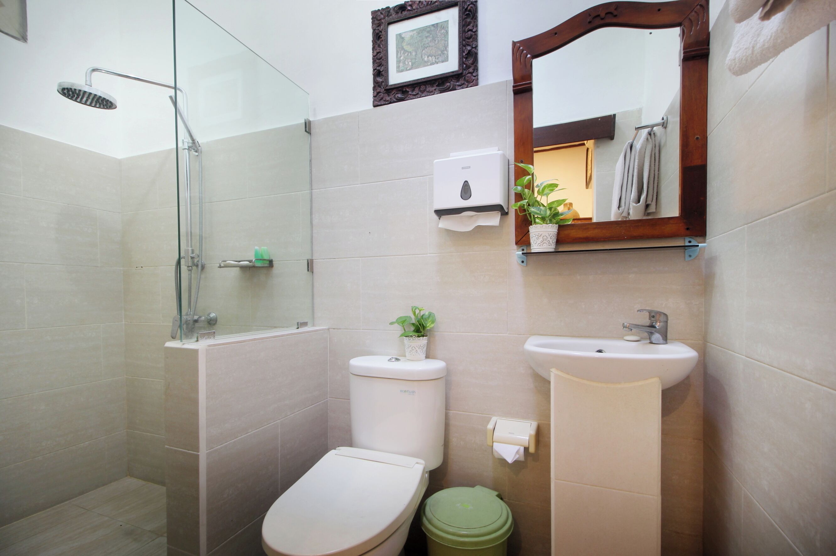 A bathroom with a glass-enclosed shower, a toilet, a sink, and a mirror.