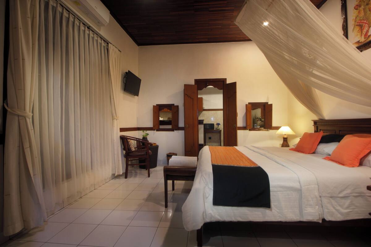 A hotel room with a bed, a chair, a desk, and a mirror.