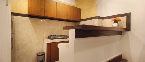 A kitchen with wooden cabinets, a countertop with a gas stove, and a trash can.