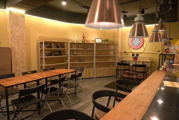 Interior de restaurante con mesas y sillas de madera, un dardo y estantes con trofeos y adornos.