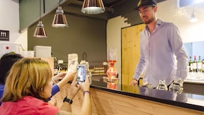 Un espace bar avec un comptoir, des bouteilles et une personne debout derrière celui-ci.
