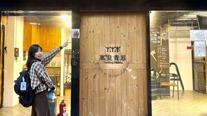 L’entrée d’un hôtel, avec une porte en bois, un extincteur et une enseigne avec des caractères japonais.