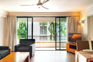 A modern living room with a sofa, a coffee table, a TV, and a dining area with a table and chairs. - Saigon Apartments (Ho Chi Minh City)