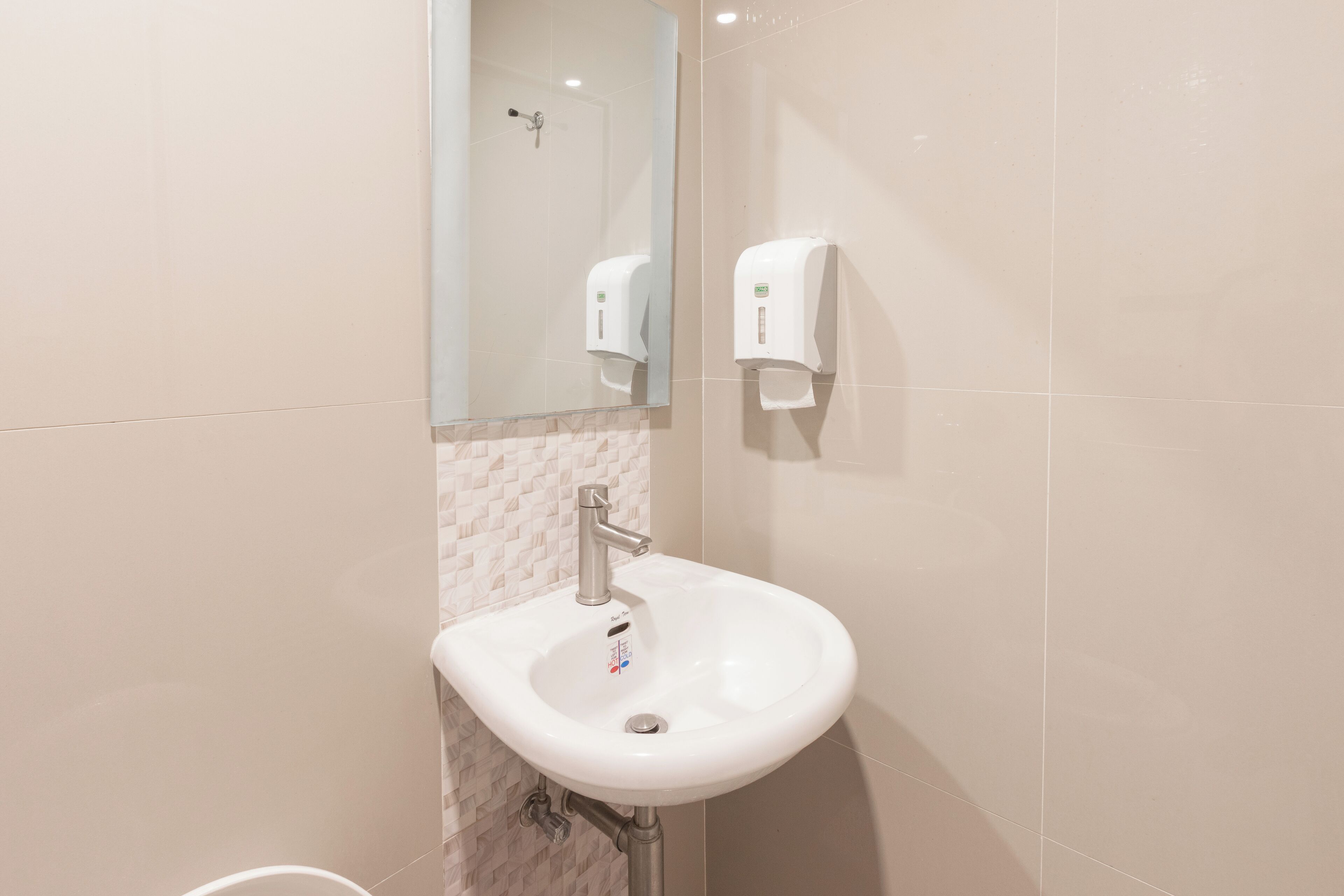 A bathroom with a white sink, a mirror, and two hand sanitizer dispensers.