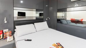 A modern hotel room with a large bed, a bedside table with a phone and remote control, and a mirror on the wall. - Hotel Sogo Cainta (Pasig)
