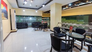 A modern restaurant with a clean, tiled floor and a mix of black and wooden furniture. There are multiple tables and chairs, and a decorative wall with a fan pattern. - Hotel Sogo Cainta (Pasig)