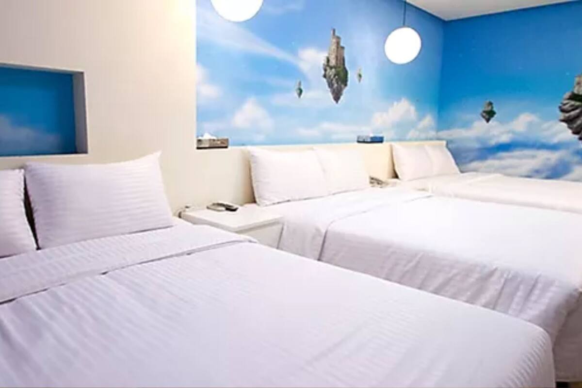 A hotel room with two beds, a nightstand, and a wall mural of floating islands.