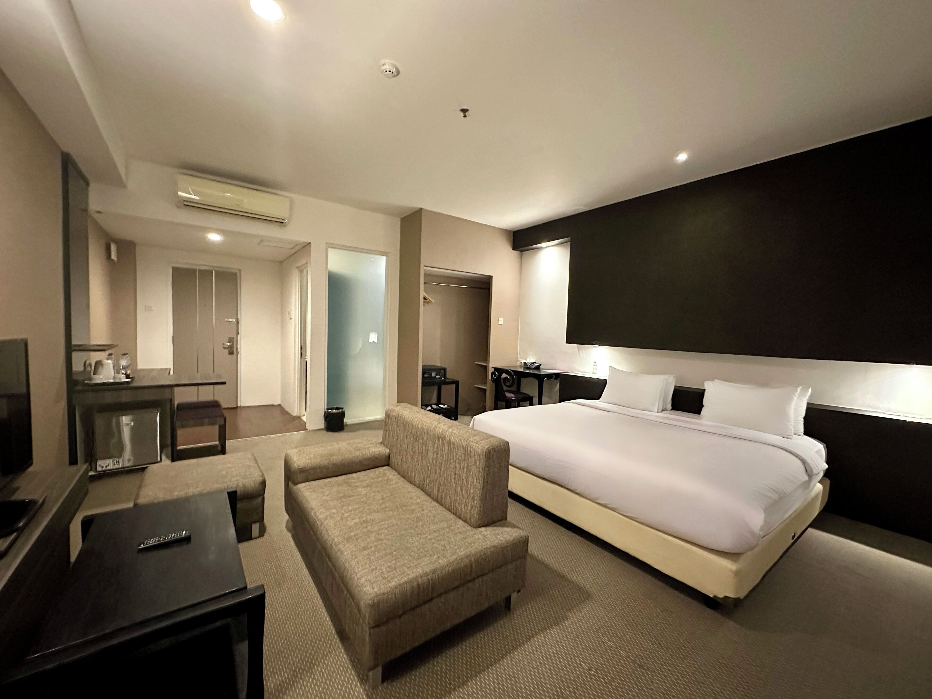Une chambre d’hôtel avec un grand lit, un bureau, une chaise, une télévision et une armoire.