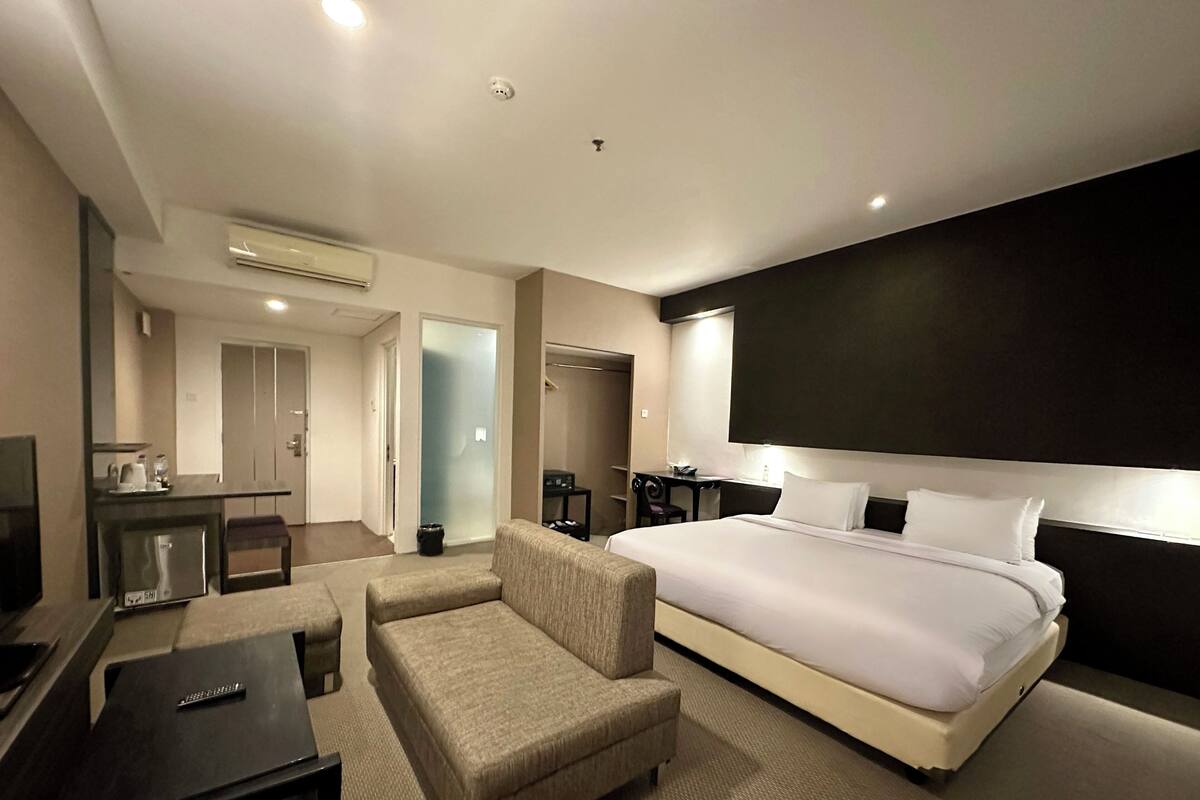 Una habitación de hotel con una cama grande, un escritorio, una silla, un televisor y un armario.