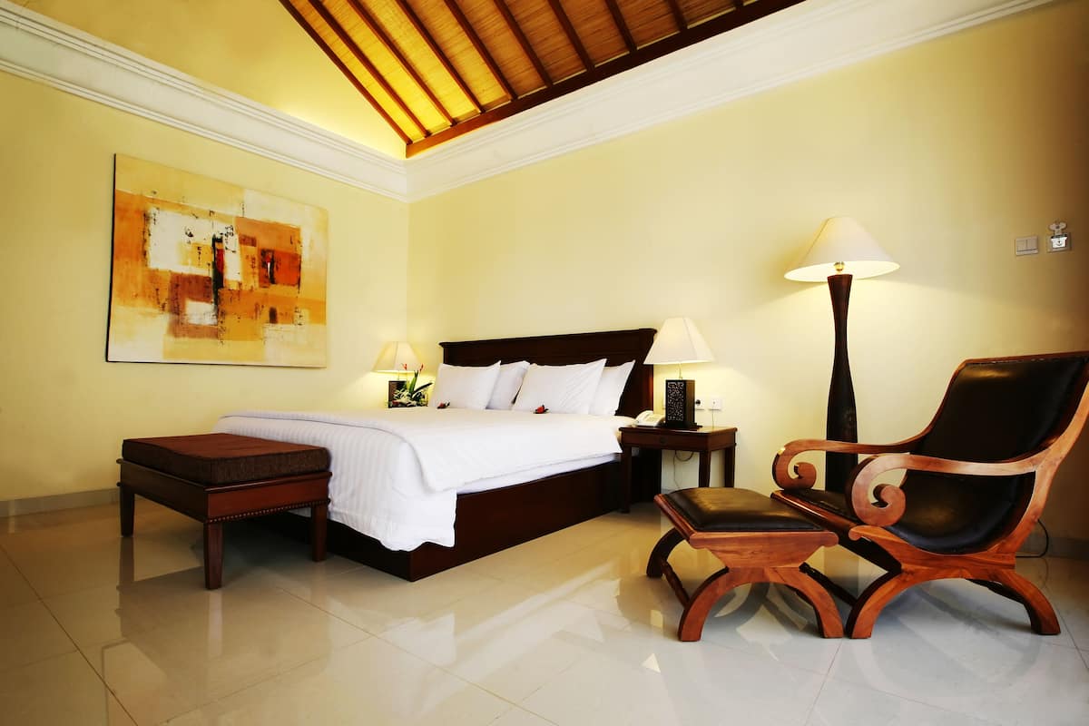 A neatly arranged bedroom with a bed, bedside tables, a chair, and a lamp.