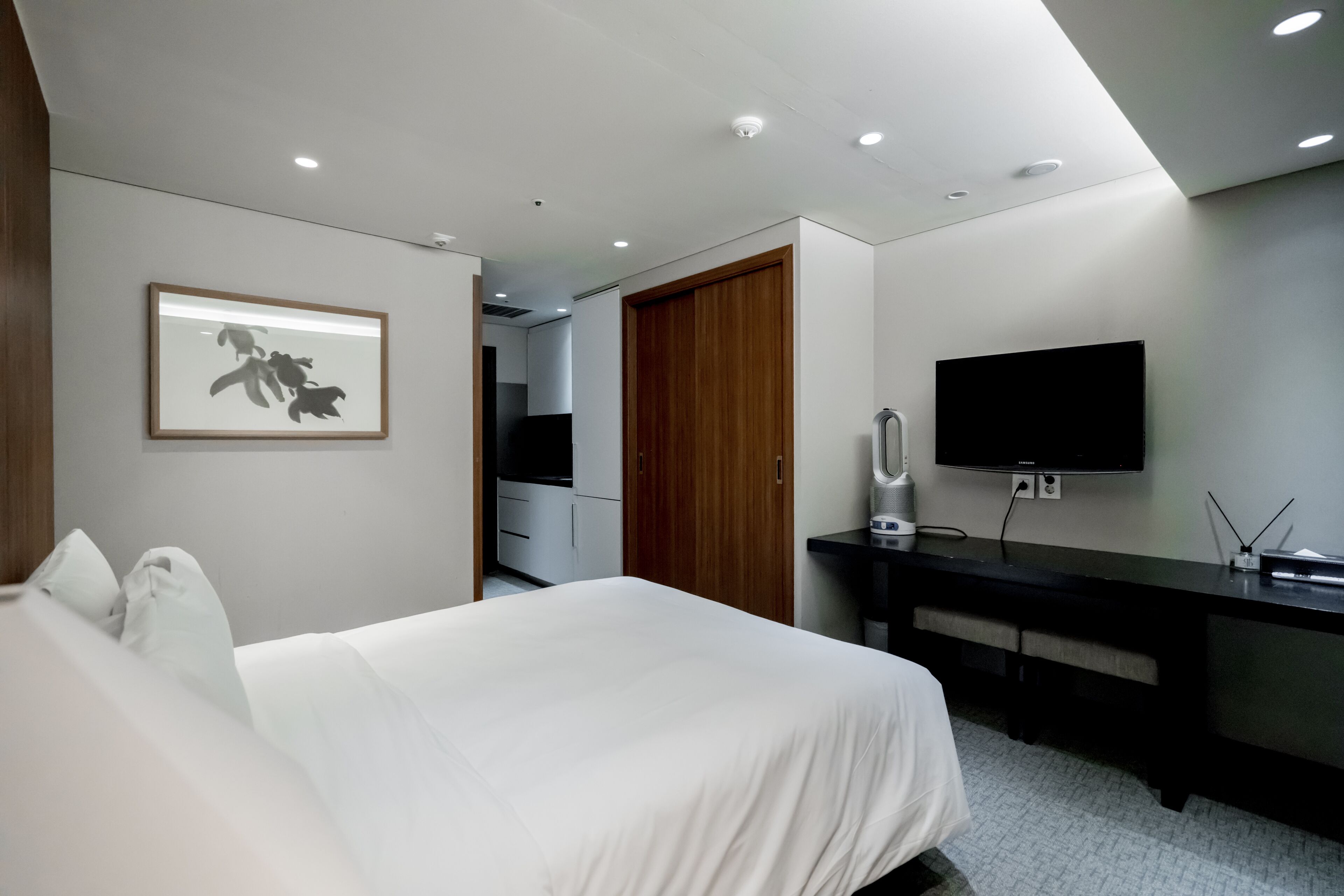 Une chambre d’hôtel moderne équipée d’un grand lit, d’un bureau, d’une télévision à écran plat et d’une armoire en bois.