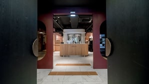 Una zona de recepción con mostrador de madera, una lámpara moderna y suelo de baldosas.