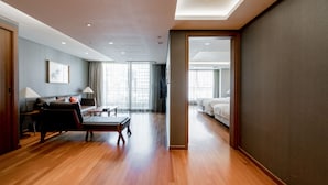 Una habitación de hotel amplia con suelo de madera, un sofá, un escritorio y una cama.