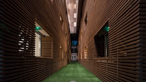 Un pasillo estrecho con listones de madera en las paredes y una alfombra verde.