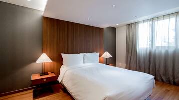 A modern hotel room with a large bed, wooden paneling on the walls, and a window with curtains.