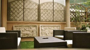 A seating area with wicker furniture and decorative wall panels. - Demi's Home (Rome)