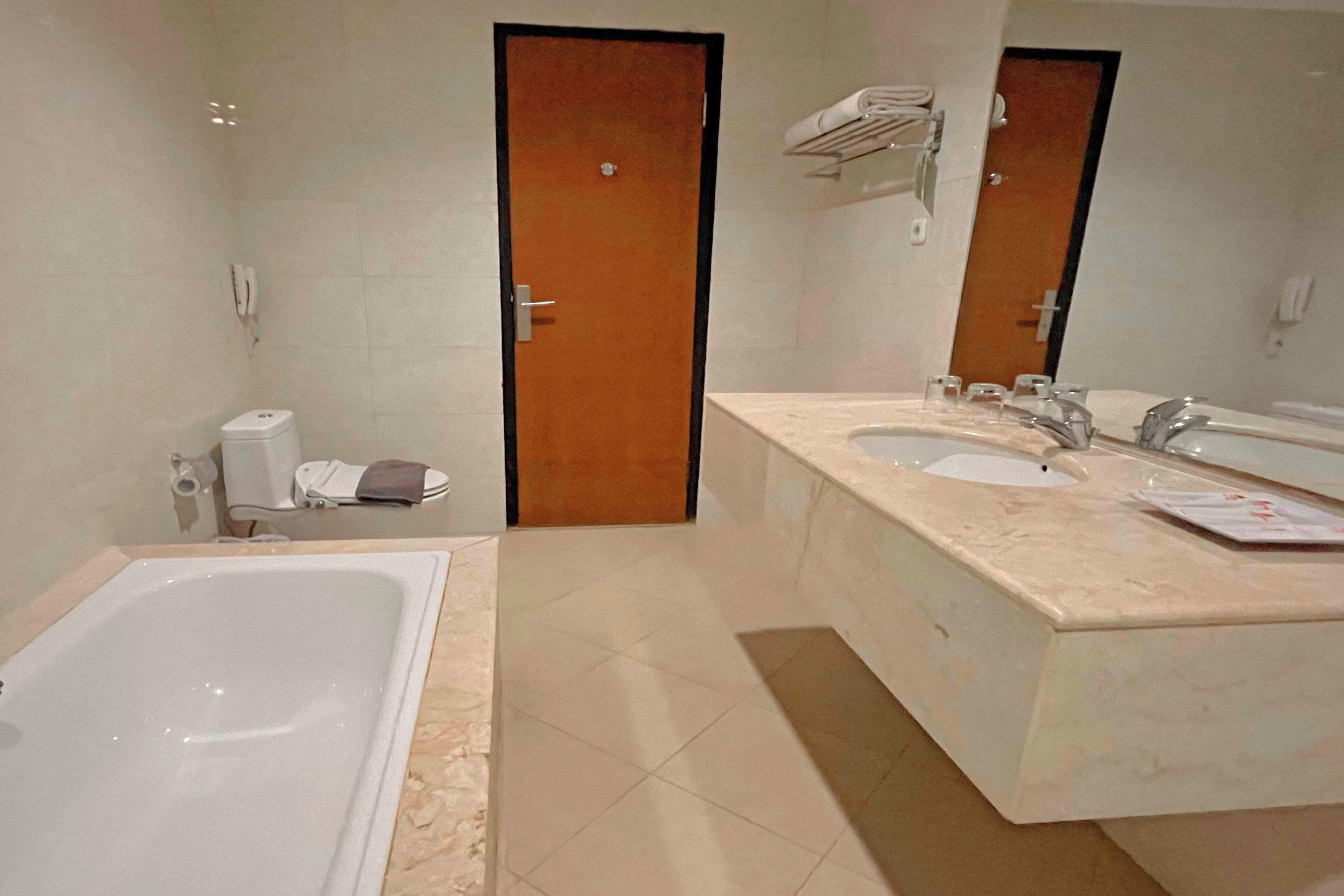 Une salle de bain avec une baignoire, deux lavabos et un miroir.