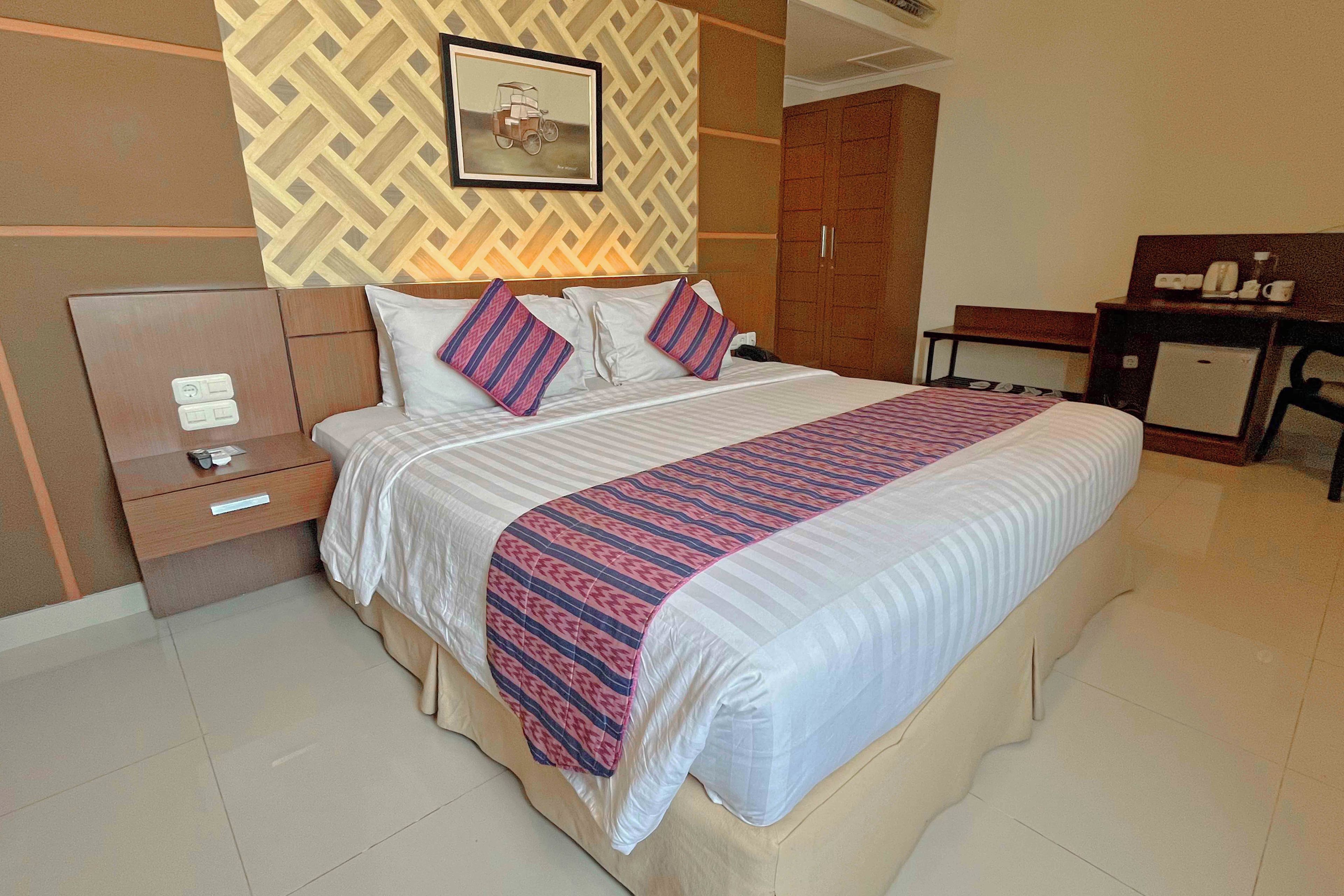 Una habitación de hotel con cama, mesitas de noche, escritorio y armario.