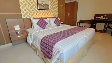 A hotel room with a bed, bedside tables, a desk, and a wardrobe.