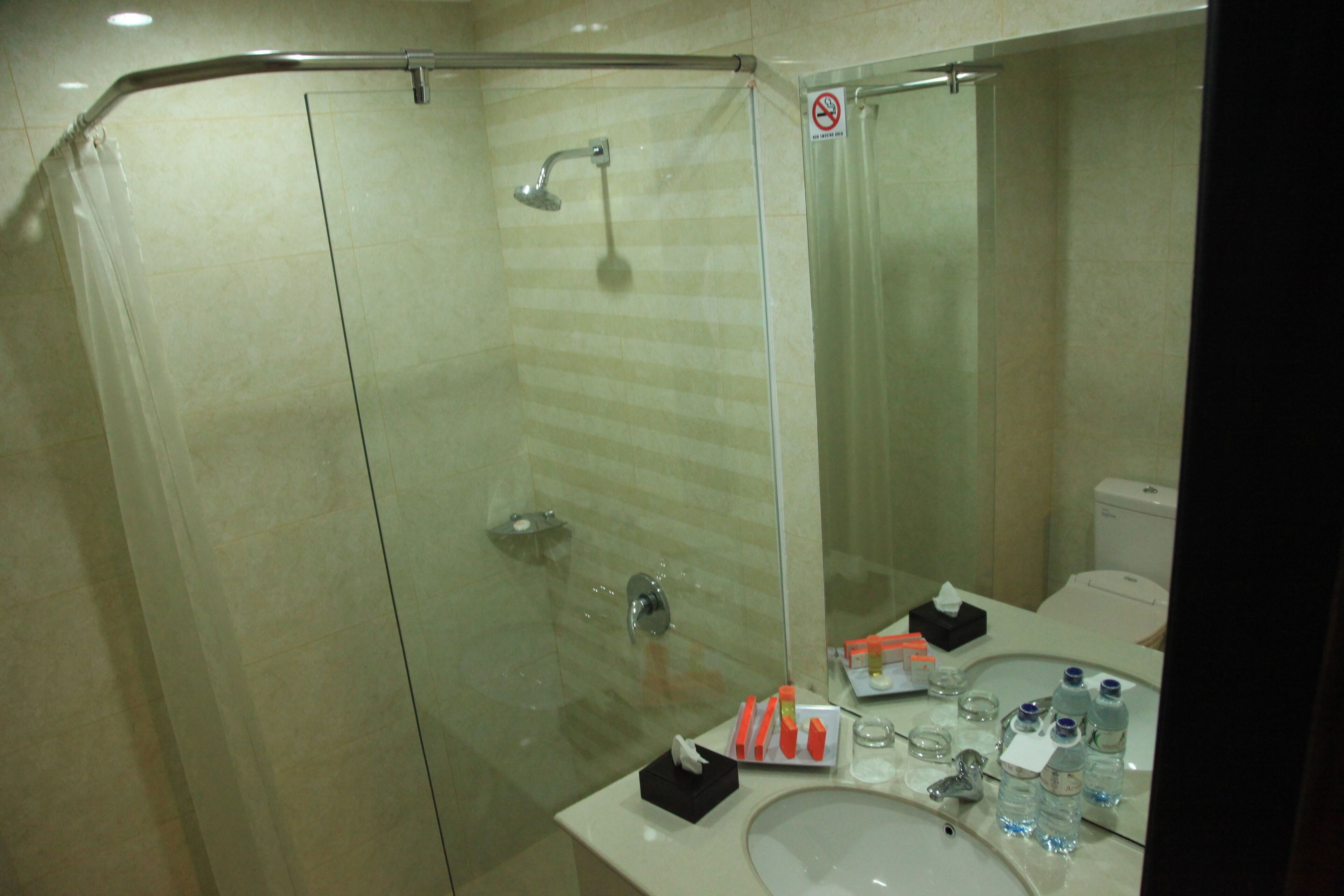 Un baño con cabina de ducha de vidrio, lavabo con artículos de aseo y retrete.