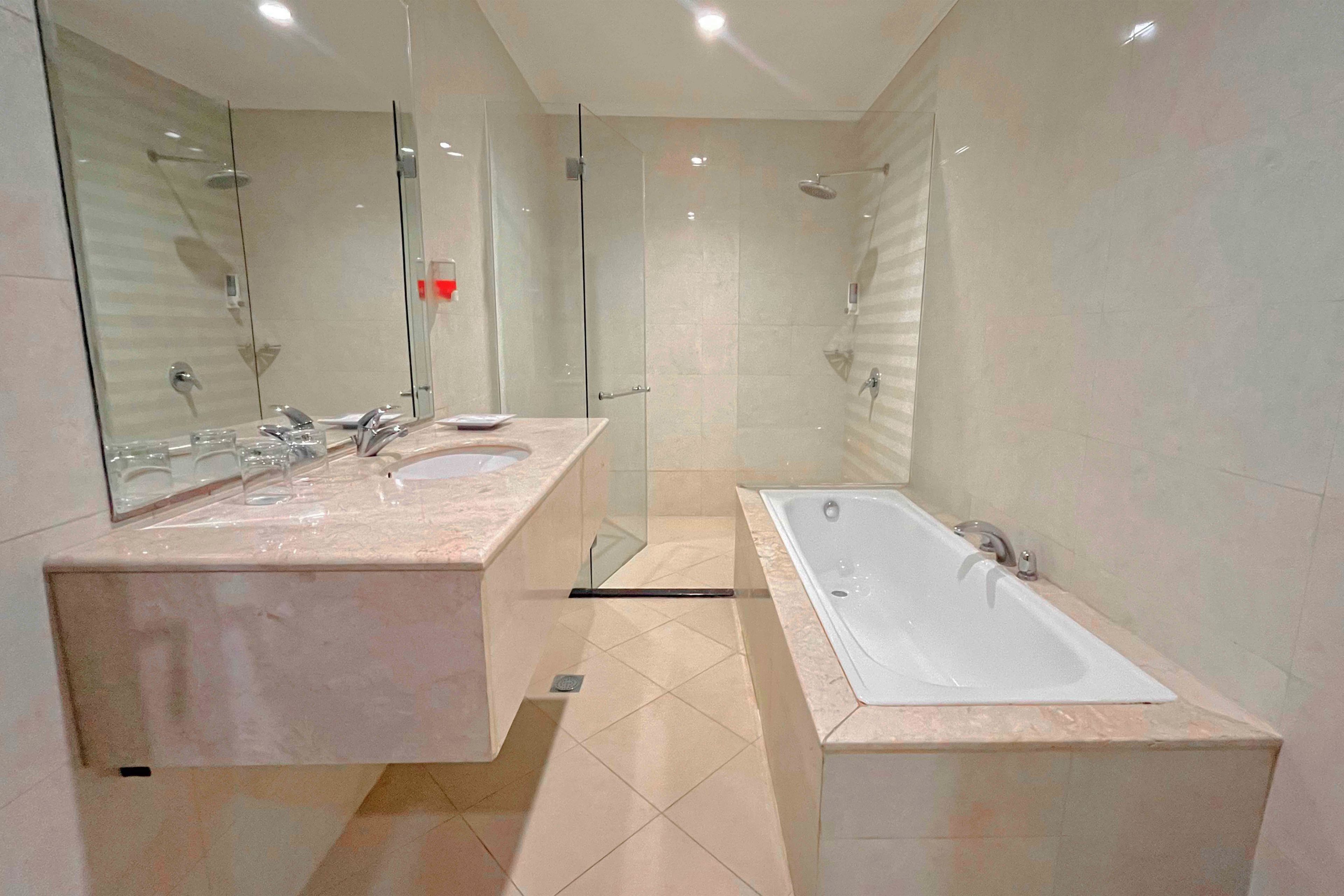 Een moderne badkamer met een wastafelmeubel met dubbele wastafel, een grote spiegel en een losstaand bad.