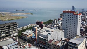 A high-rise hotel with multiple floors, a prominent red and white color scheme, and a view of the sea and port in the background. - Aerotel Smile Makassar (Makassar)