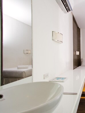 A modern bathroom with a large mirror, a white sink, and a towel rack. - Ellis Ecotel (Legazpi)