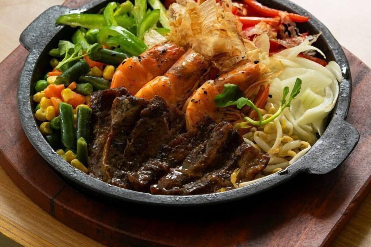 A meal with a variety of dishes including a bowl of rice, a plate with vegetables, meat, and seafood.