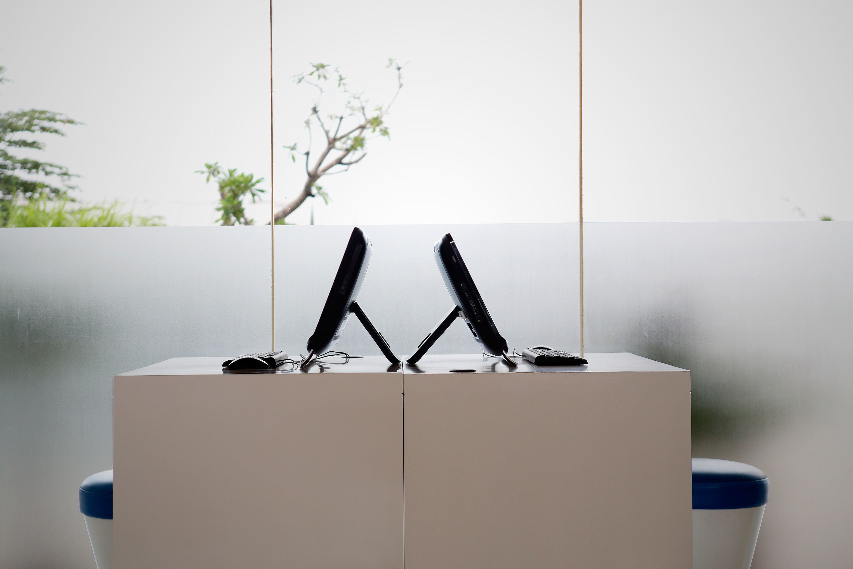 A modern, minimalist room with a white desk and two black chairs.