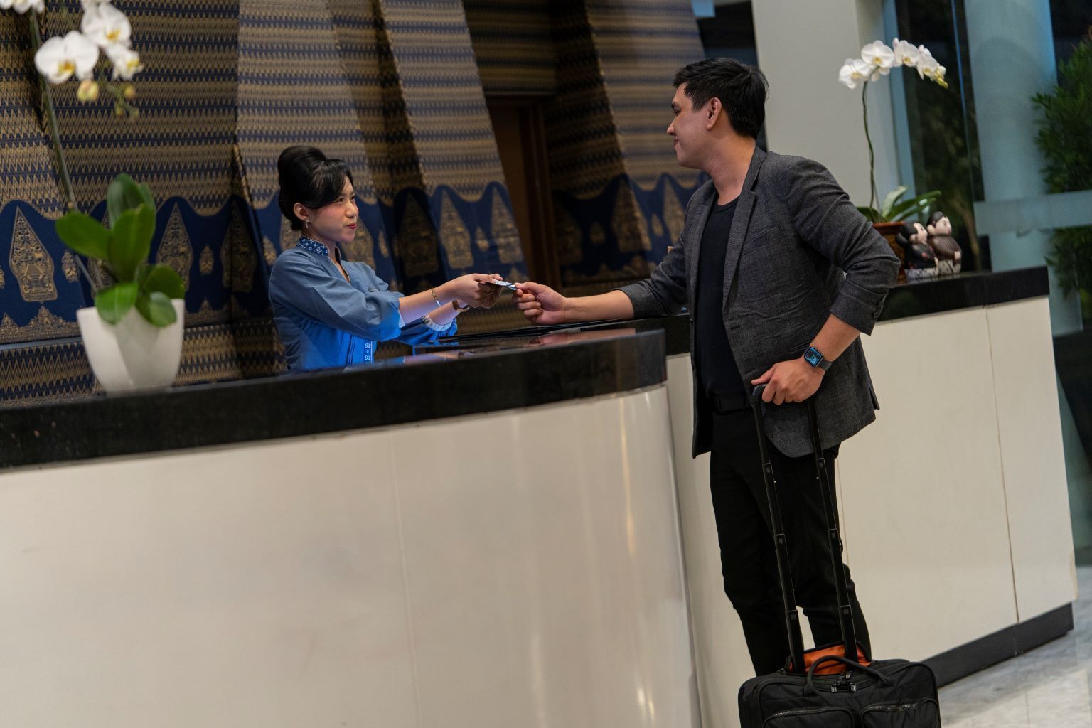 Zona de recepción de un hotel con un recepcionista y un huésped.