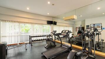 A gym with treadmills, elliptical machines, and a rack of dumbbells.