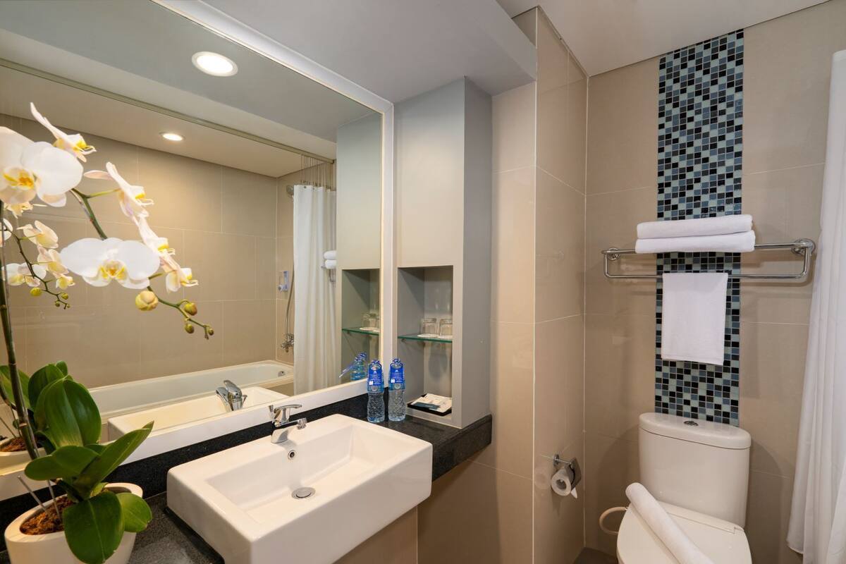 A modern bathroom with a sink, mirror, toilet, and shower.