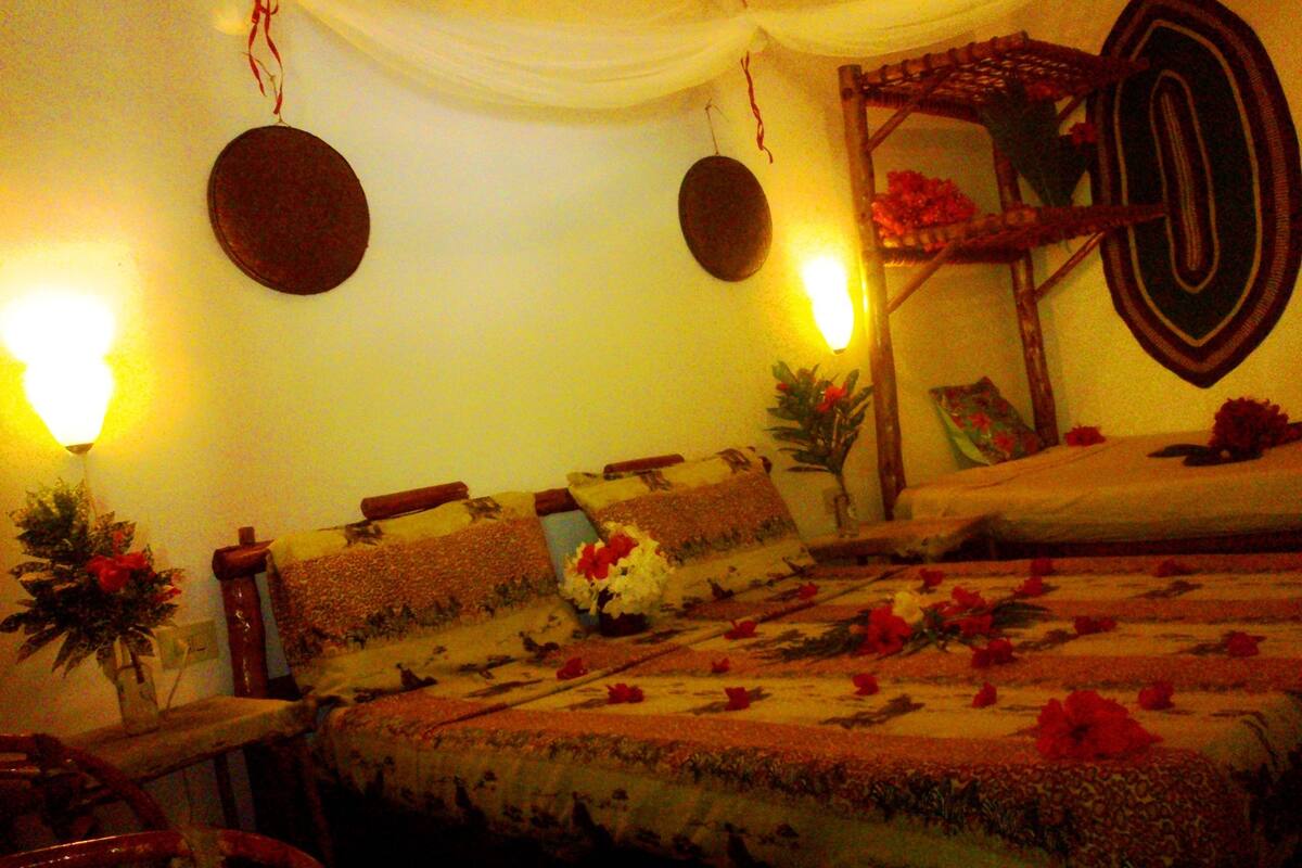 Una habitación con una cama, cabecera de madera y un espejo decorativo en la pared.
