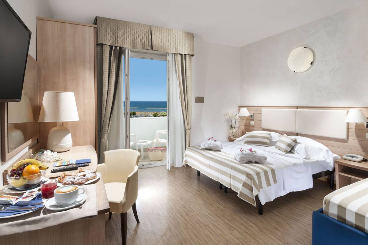 Ein Hotelzimmer mit Bett, Schreibtisch mit Stuhl, Fernseher und Meerblick.