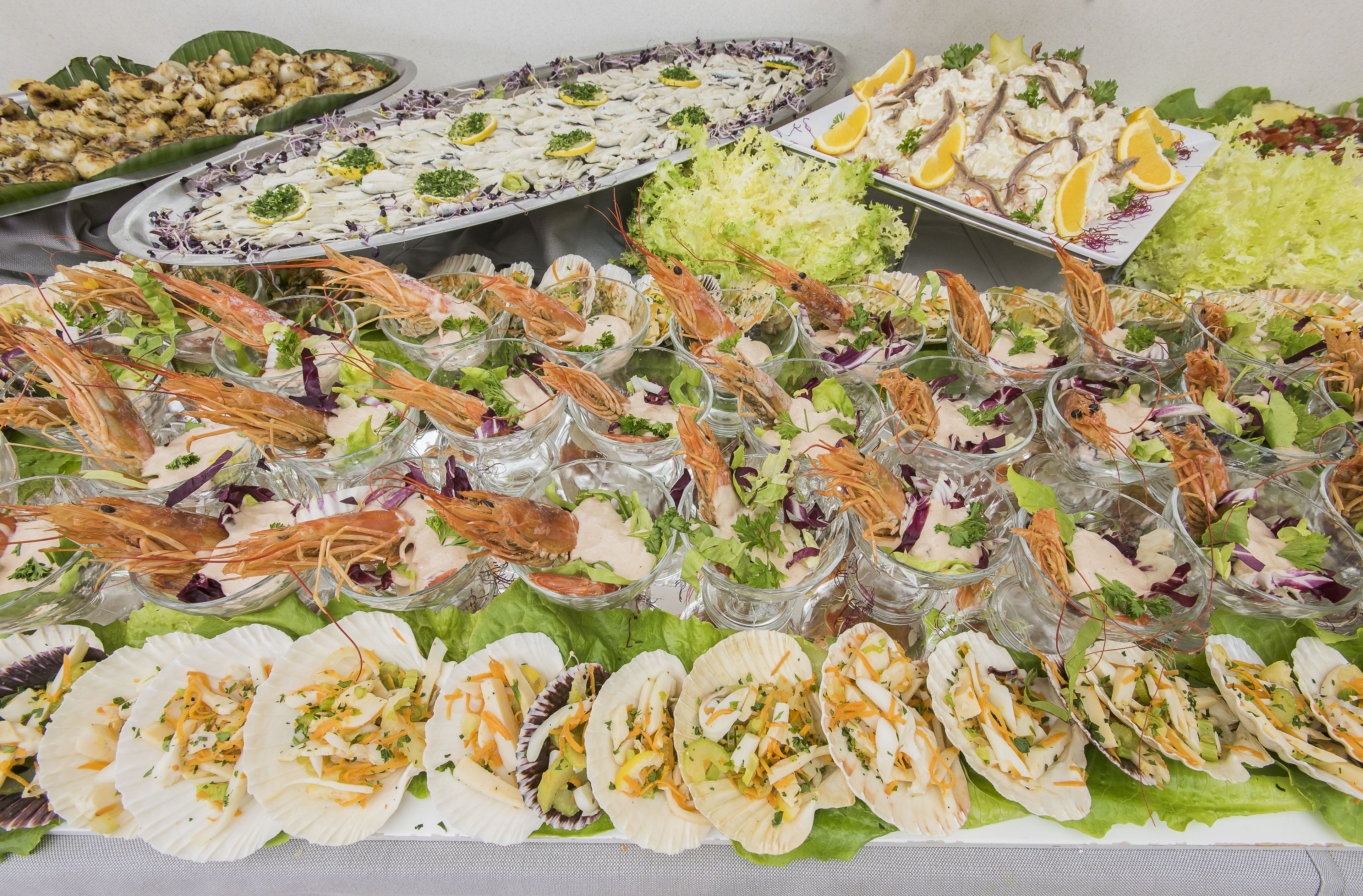 Une variété de plats de fruits de mer, notamment des crevettes et des huîtres, disposés sur une table.