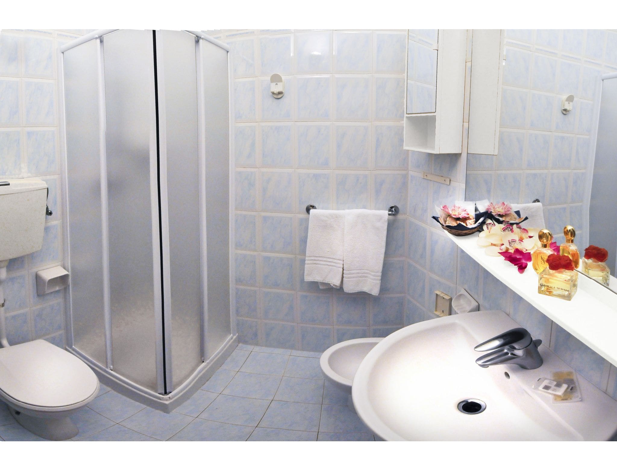 Ein Badezimmer mit Dusche, Toilette, Waschbecken und einem Handtuchhalter mit einem weißen Handtuch.