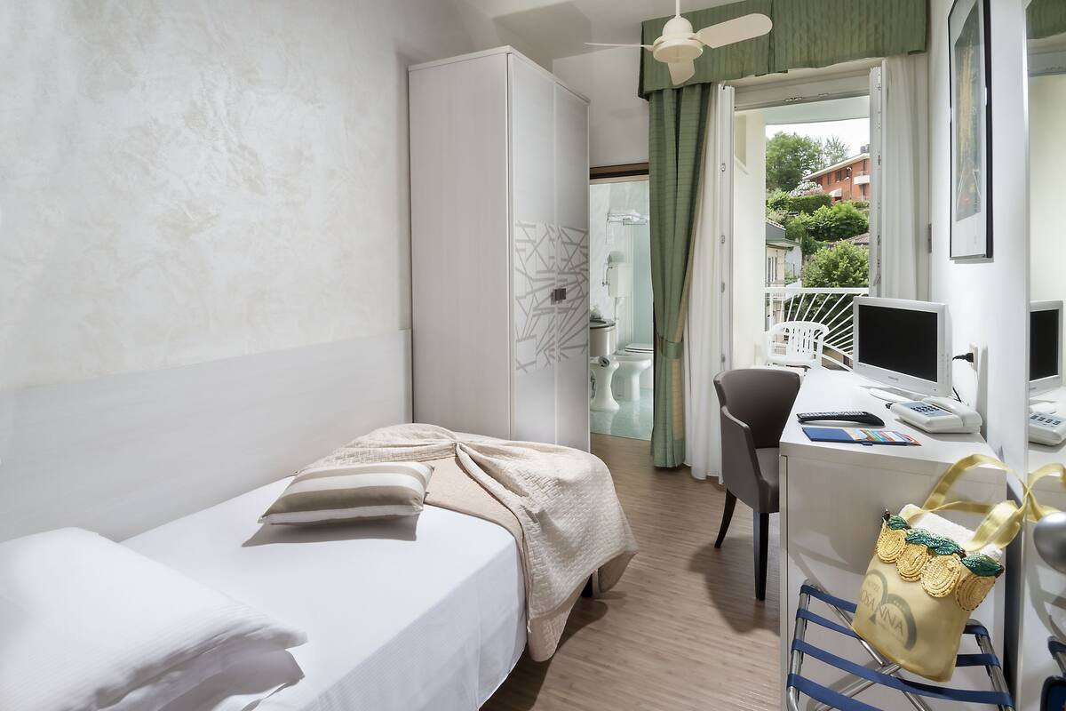 Ein Hotelzimmer mit Bett, Schreibtisch mit Computer, Stuhl und Kleiderschrank.