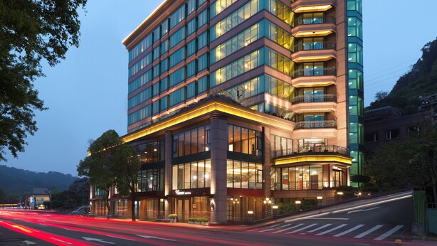 Et hotel med flere etager, moderne facade, store vinduer og en markant indgang med et markise.