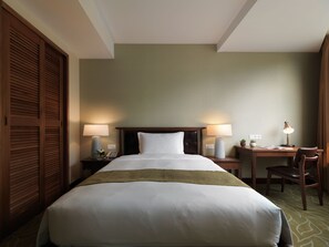 A hotel room with a large bed, two bedside tables with lamps, a desk with a chair, and a wardrobe. - Yusense Hotel (Taipei)