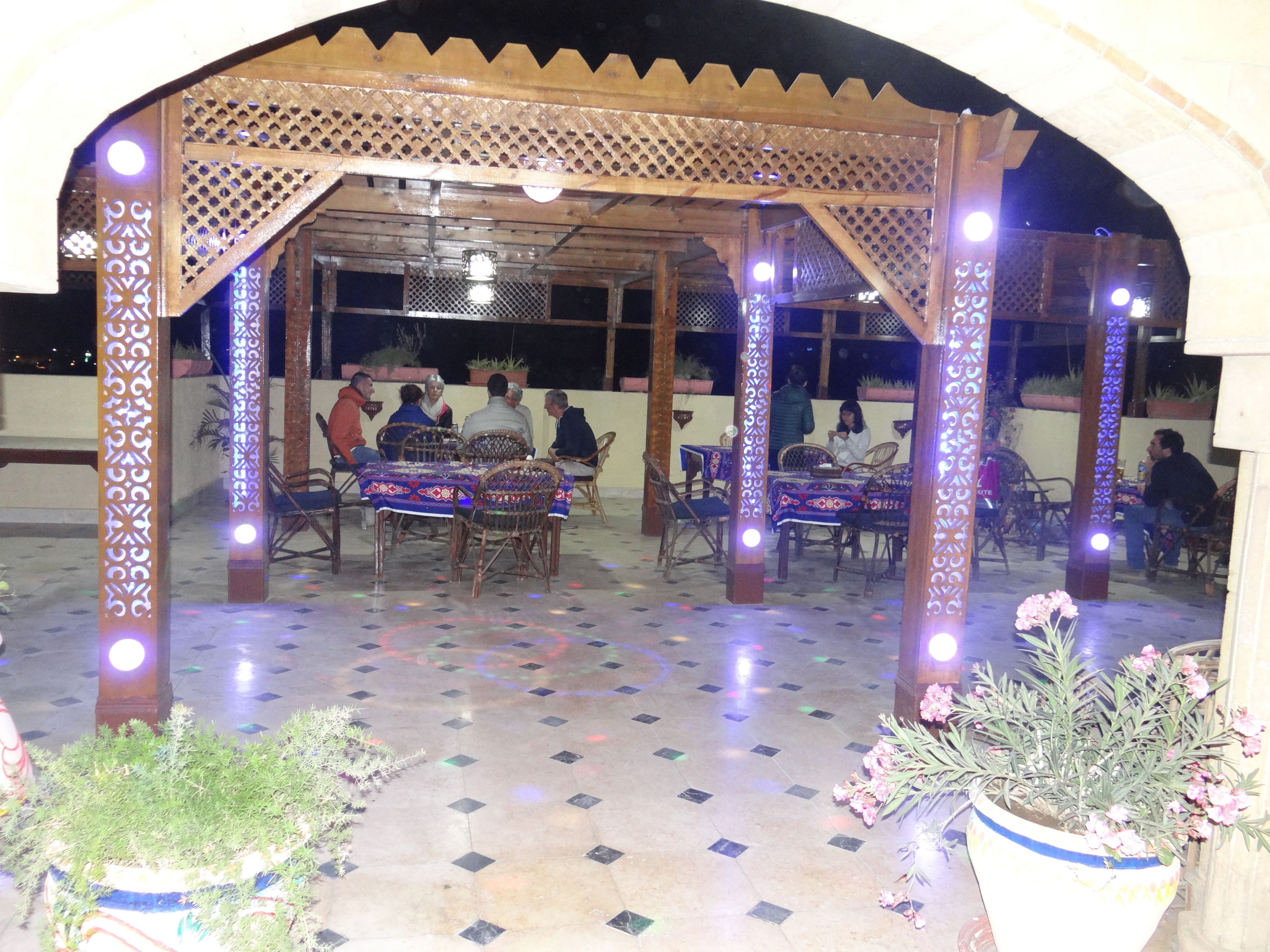 Eine Terrasse im Freien mit einer Holzpergola, Tischen und Stühlen.