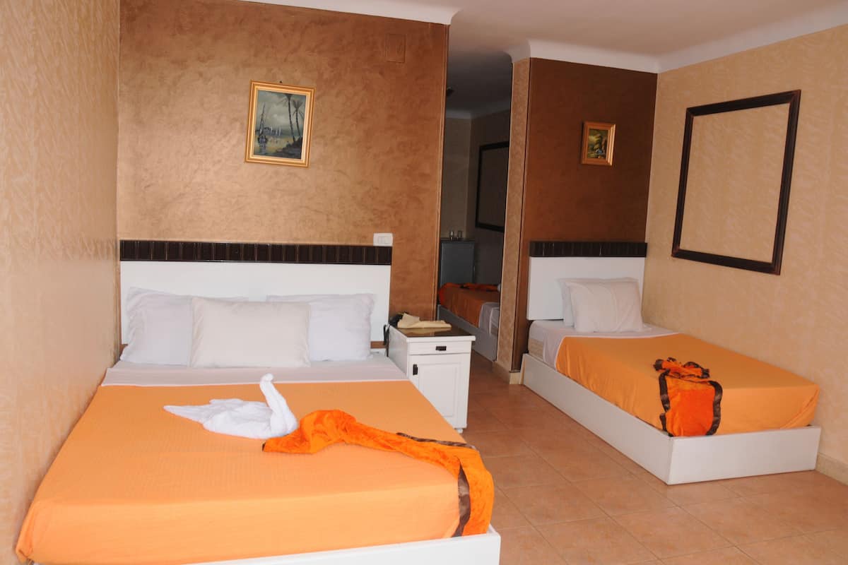 A hotel room with two beds, a nightstand, and a painting on the wall.