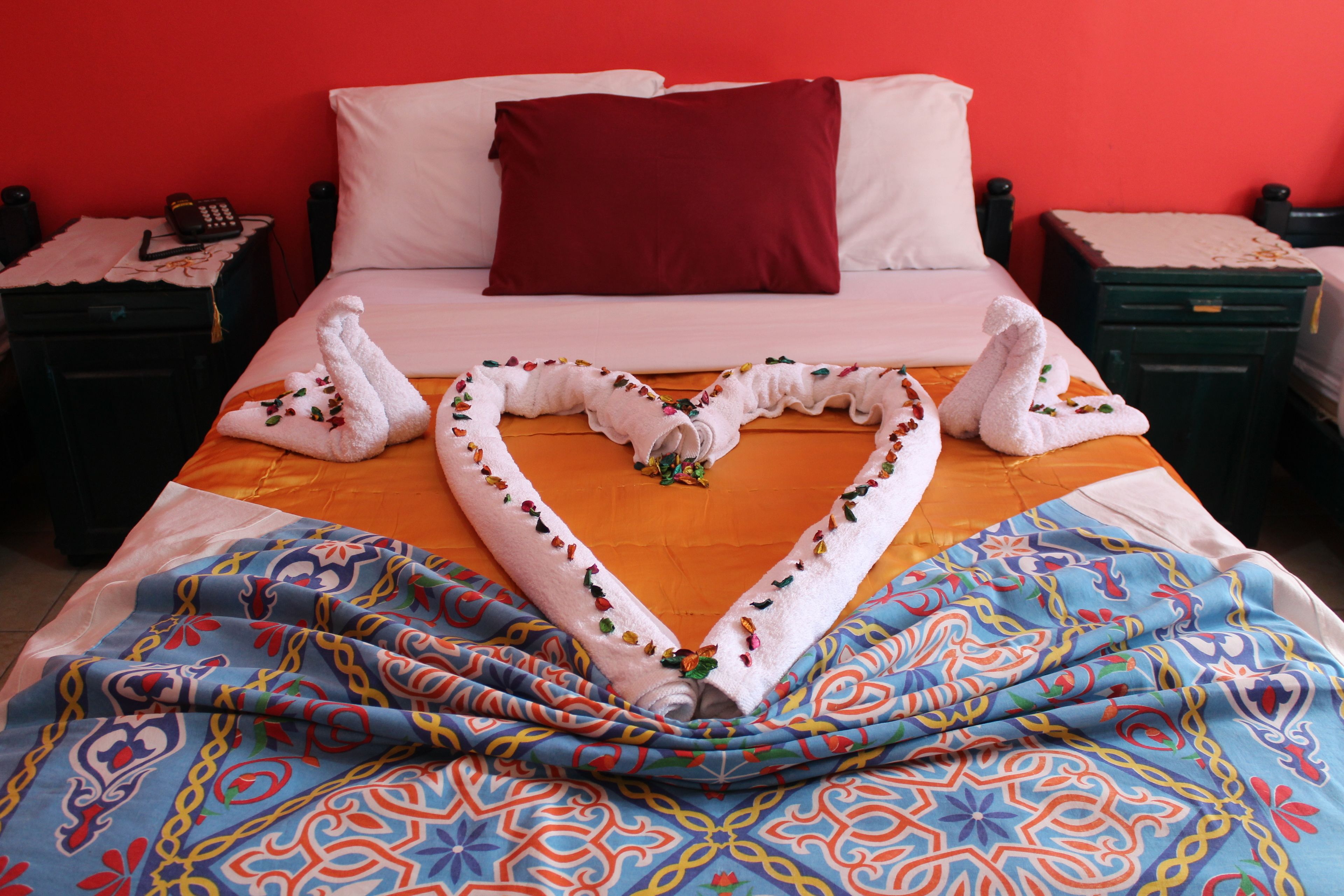 Ein Hotelzimmer mit einem Bett, einer roten Wand und einer blau gemusterten Bettdecke.