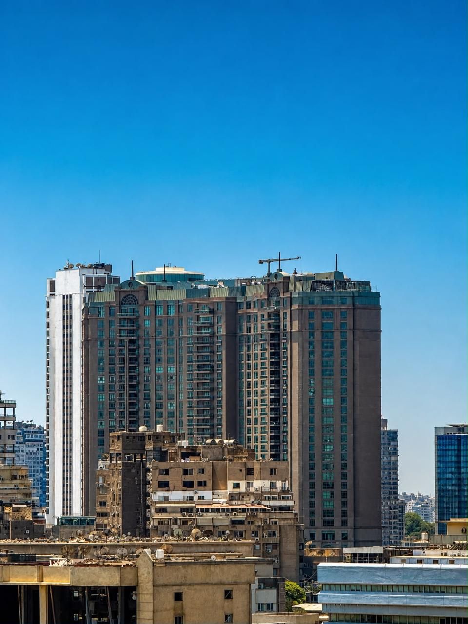 Un edifici alt amb múltiples plantes, grans finestres i una grua de construcció a la part superior.