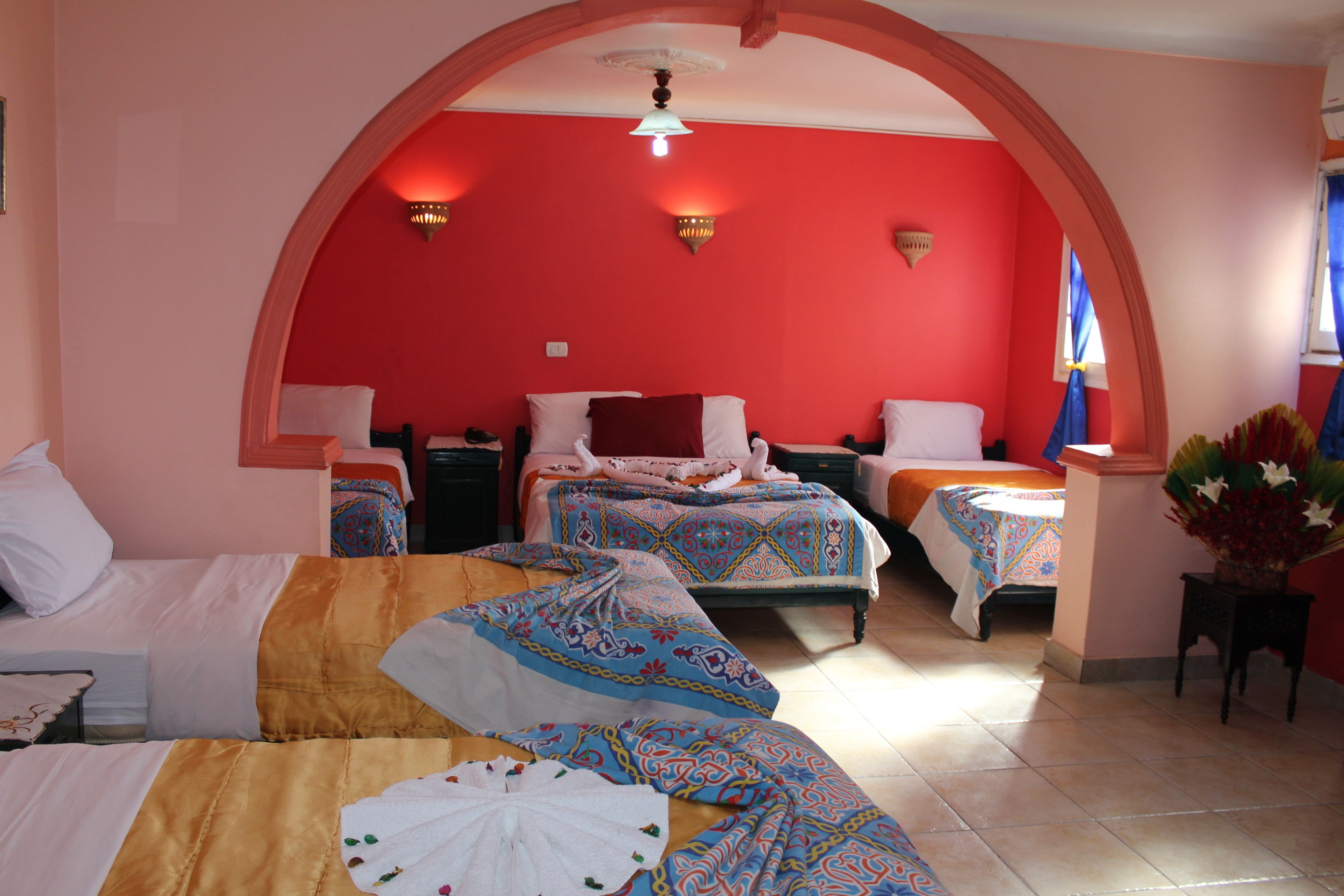 A hotel room with two beds, a sitting area, and a small table with a vase.
