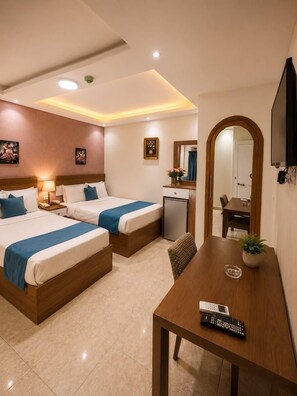 Habitación de hotel con dos camas, un escritorio, una silla, un televisor y una kitchenette pequeña.